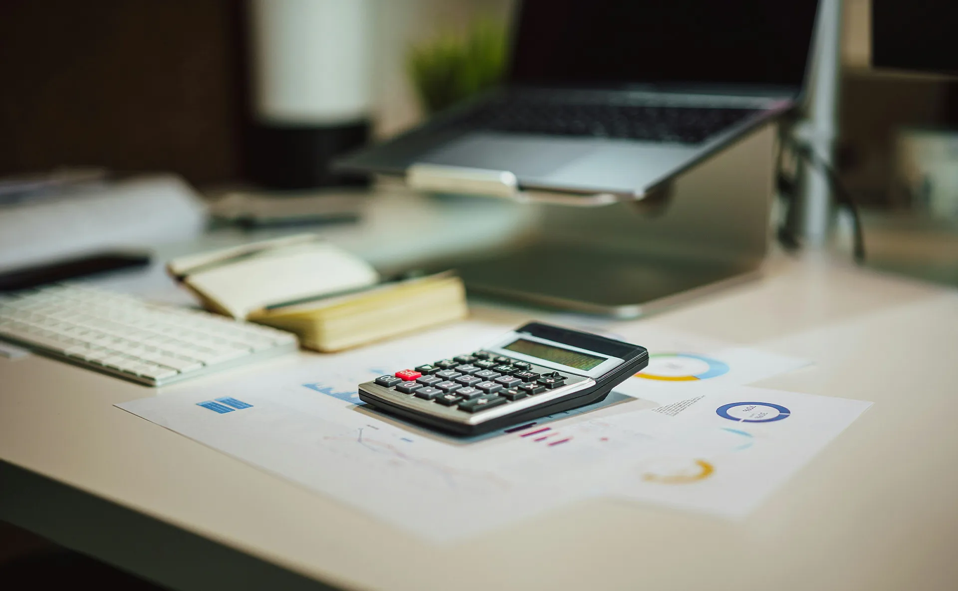 Office workspace with calculator, charts, and laptop representing Quickbooks integration