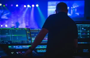Silhouette of a technician managing lighting console screens for AV inventory management during a live event setup