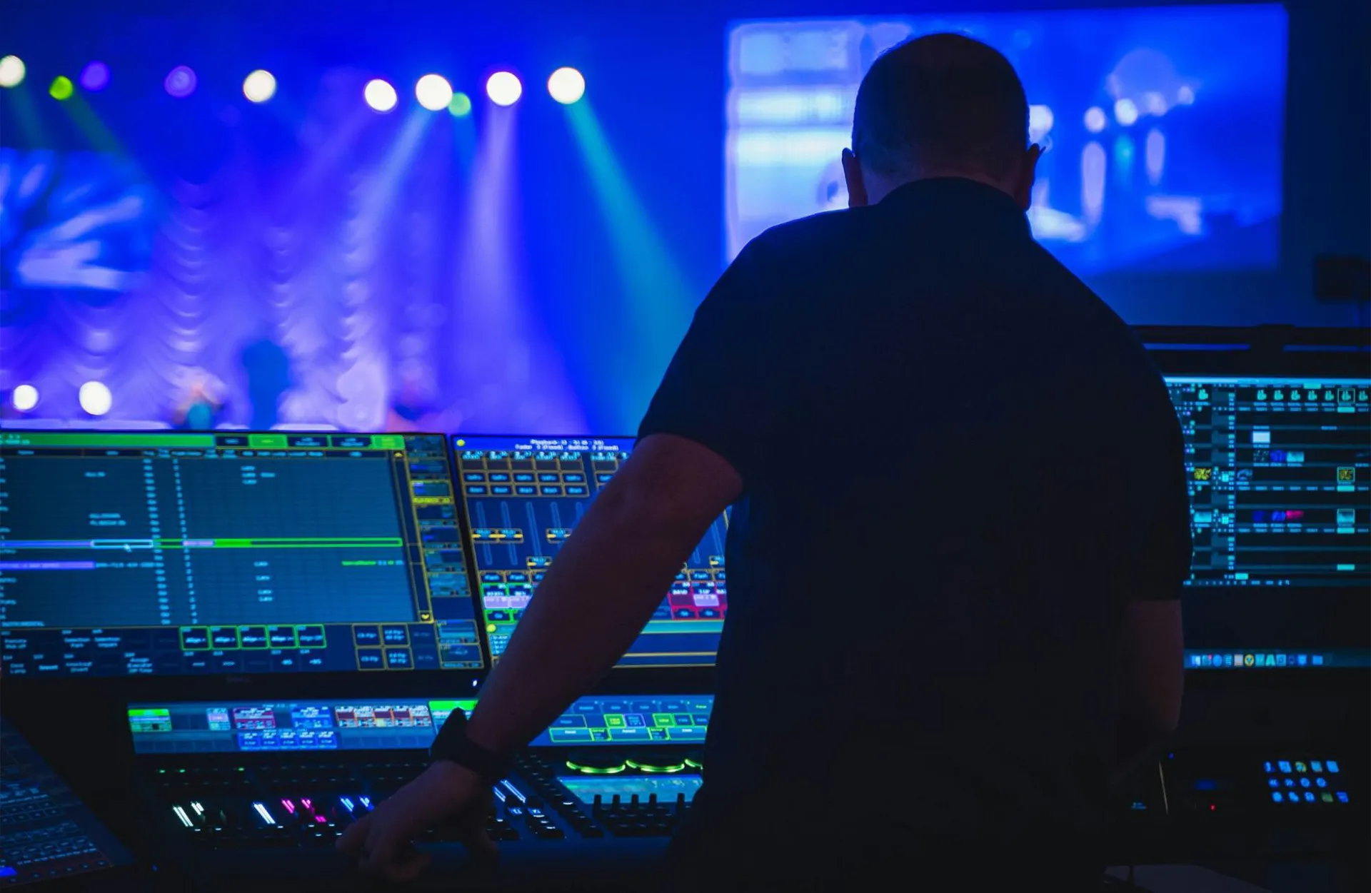Silhouette of a technician managing lighting console screens for AV inventory management during a live event setup